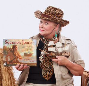 Anthropologist Annie holding up a book and model ship